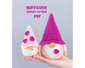 May include: Two crocheted gnome figures, one pink and one purple, are displayed. The gnomes have conical hats and heart-shaped accents. The text "MUFFICORN CROCHET PATTERN PDF" is at the top. The gnomes are held in a hand.