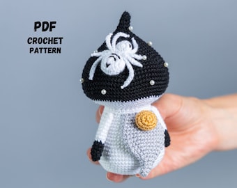 May include: Crochet amigurumi pattern for a black and white mushroom with a spider on top. The mushroom has a white body and a black cap with white beads. The spider is white with black eyes. The pattern is available as a PDF download.
