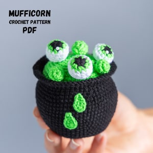 May include: A crocheted cauldron with green goo and eyeballs on top. The cauldron is black with green accents. The text "MUFFICORN CROCHET PATTERN PDF" is at the top of the image.