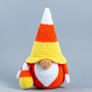 May include: A crocheted candy corn gnome with a white beard and a yellow, orange, and white candy corn hat.