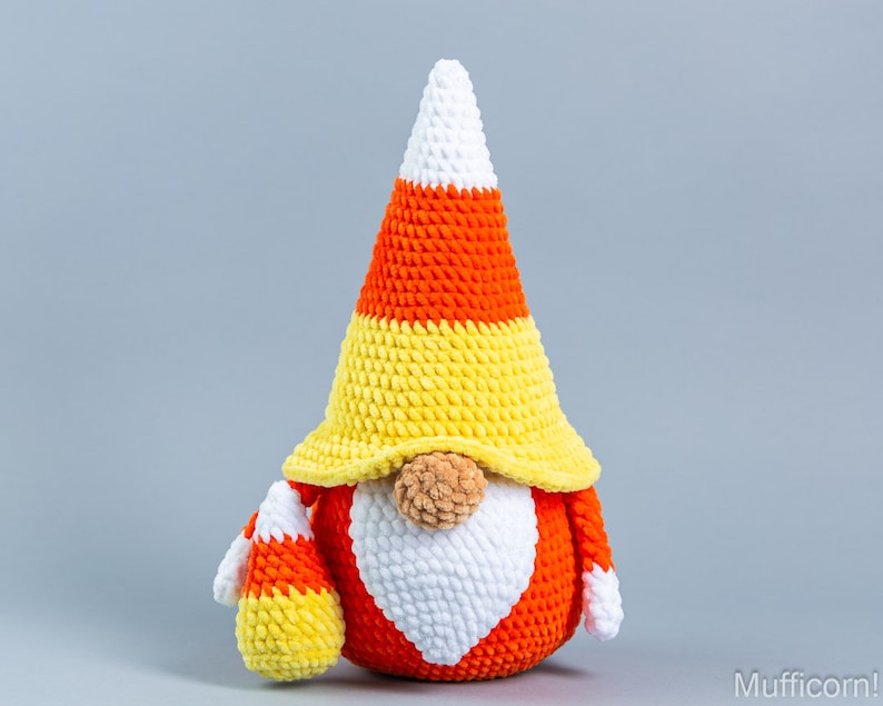 May include: A crocheted candy corn gnome with a white beard and a yellow, orange, and white candy corn hat.
