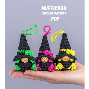 Può includere: Tre ornamenti di gnomi all'uncinetto neri con accenti colorati. Ogni gnomo ha un cappello a punta e una barba. Il testo "MUFFICORN CROCHET PATTERN PDF" è nella parte superiore dell'immagine.