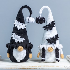 May include: Two crocheted Halloween gnomes, one black and one white, with black and white bats and pumpkins on their hats.