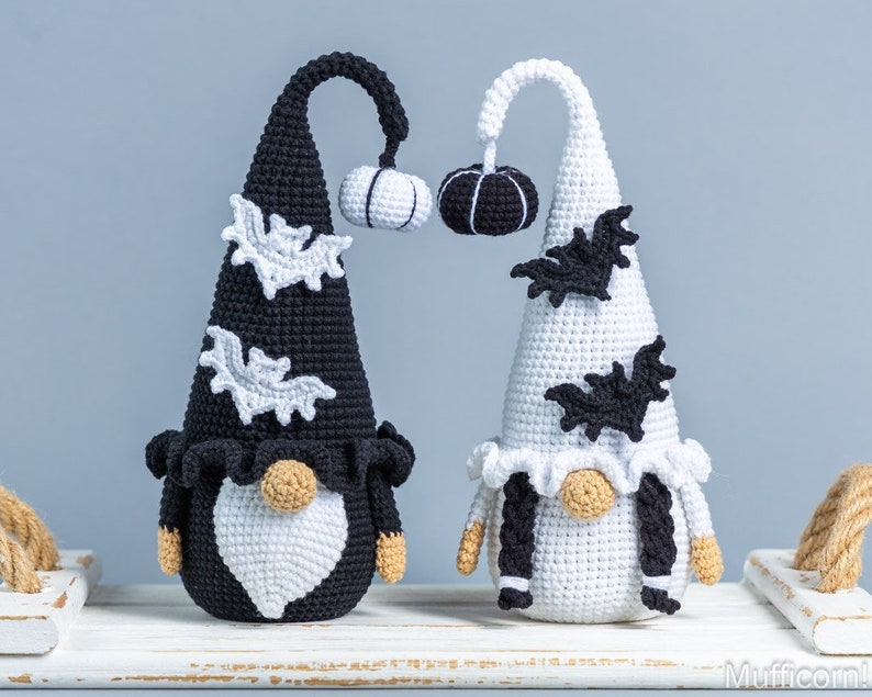 May include: Two crocheted Halloween gnomes, one black and one white, with black and white bats and pumpkins on their hats.