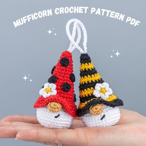 Puede incluir: Dos gnomos de crochet, uno con un gorro de mariquita rojo y negro y el otro con un gorro de abeja amarillo y negro. Ambos gnomos tienen caras blancas y barbas blancas.
