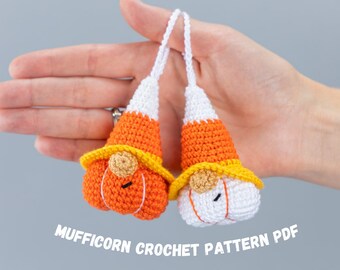 May include: Two crocheted candy corn gnomes with orange, yellow, and white yarn. The gnomes are holding pumpkins. The image includes the text "Mufficorn Crochet Pattern PDF".