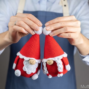 May include: Two crocheted gnome ornaments in red and white. The gnomes have white beards and white hats with white pom-poms.