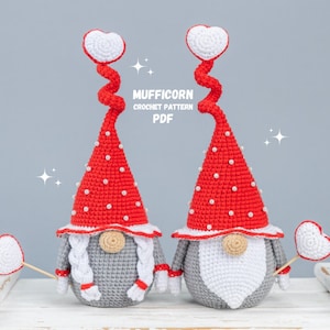 May include: Two crocheted gnomes with red hats and white hearts on top. The gnomes have white beards and are holding white heart-shaped wands. The text "MUFFICORN CROCHET PATTERN PDF" is visible in the image.