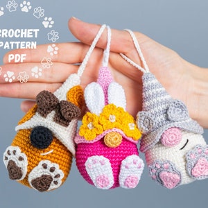 Peut inclure: Trois ornements de gnome en crochet, un marron avec des accents blancs, un rose avec des accents jaunes et un blanc avec des accents gris. Chaque gnome porte un petit chapeau en crochet.