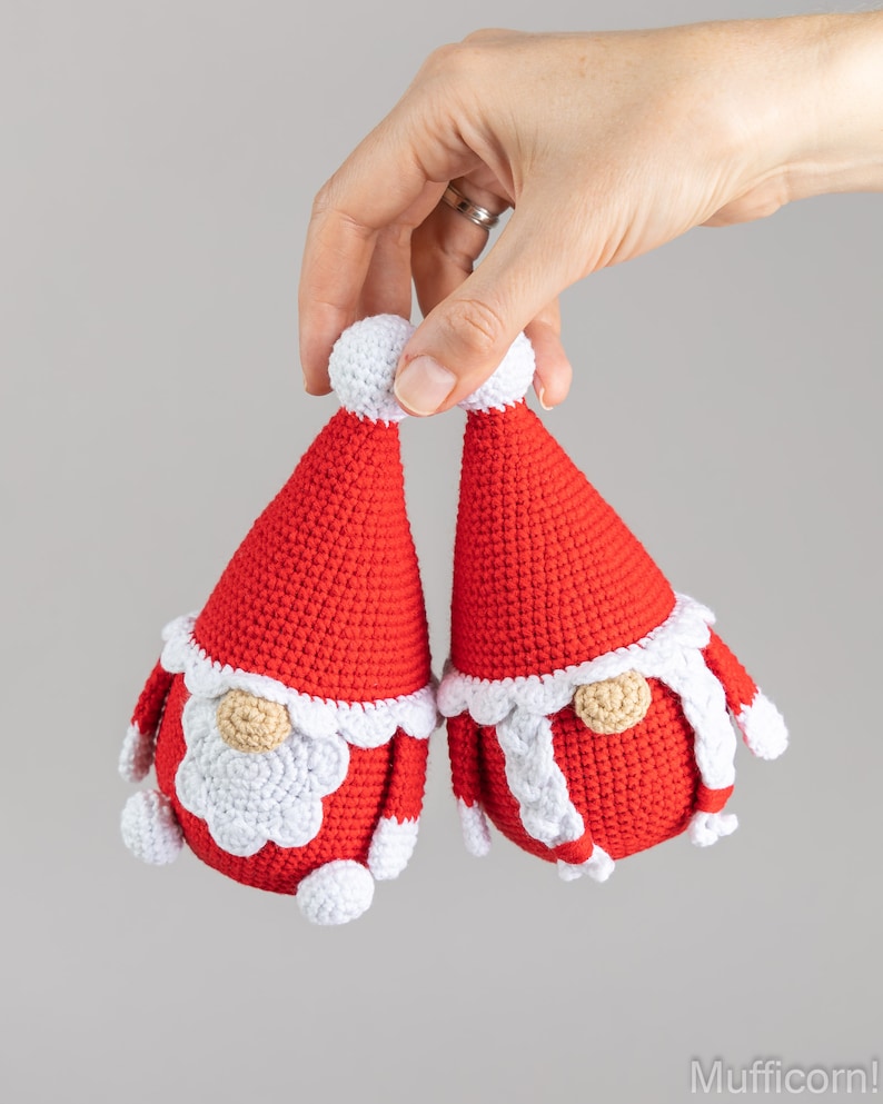 May include: Two crocheted gnome ornaments in red and white. The gnomes have white beards and white pom-poms on their hats.