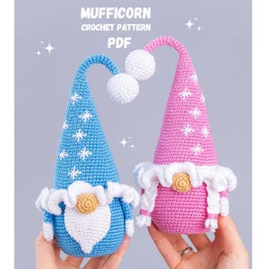 Może przedstawiać: Dwie szydełkowe figurki gnomów, jedna niebieska i jedna różowa, z białymi akcentami i detalami gwiazd. Gnomy mają białe brody, a obraz zawiera tekst "MUFFICORN CROCHET PATTERN PDF".