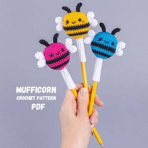 May include: Three crochet bee pencil toppers in yellow, pink, and blue, each with black stripes and white wings. The pencils are yellow. The text "MUFFICORN CROCHET PATTERN PDF" is visible.