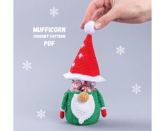 May include: Crochet pattern for a Christmas gnome with a red hat and white trim. The gnome is holding a bag of sweets. The pattern is called "Mufficorn Crochet Pattern PDF".