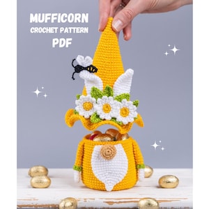 May include: A crocheted Easter gnome with a yellow hat, white beard, and a flower crown. The gnome is holding a basket filled with chocolate eggs. The text "MUFFICORN CROCHET PATTERN PDF" is visible in the image.