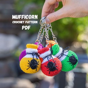 May include: A collection of colorful, crocheted potion bottle keychains. Each bottle is a different color, including yellow, red, and green, with a black spider design. The keychains are attached to silver chains and rings. Text on the image reads "MUFFICORN CROCHET PATTERN PDF".