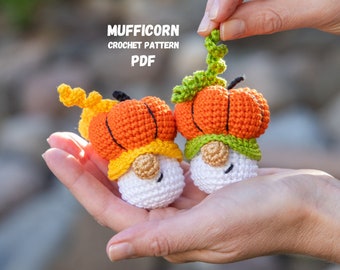 May include: Two crocheted pumpkin gnomes with white faces, orange and yellow hats, and green stems. The gnomes are being held in a person's hands. The text "MUFFICORN CROCHET PATTERN PDF" is visible above the gnomes.