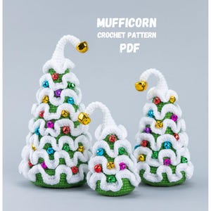May include: Three crocheted Christmas trees in varying sizes. Each tree is green with white accents, colorful ornaments, and a gold bell at the top. The text "MUFFICORN CROCHET PATTERN PDF" is displayed in the background.