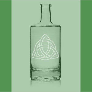 May include: A clear glass bottle with a white Celtic knot design. The bottle is on a green background.