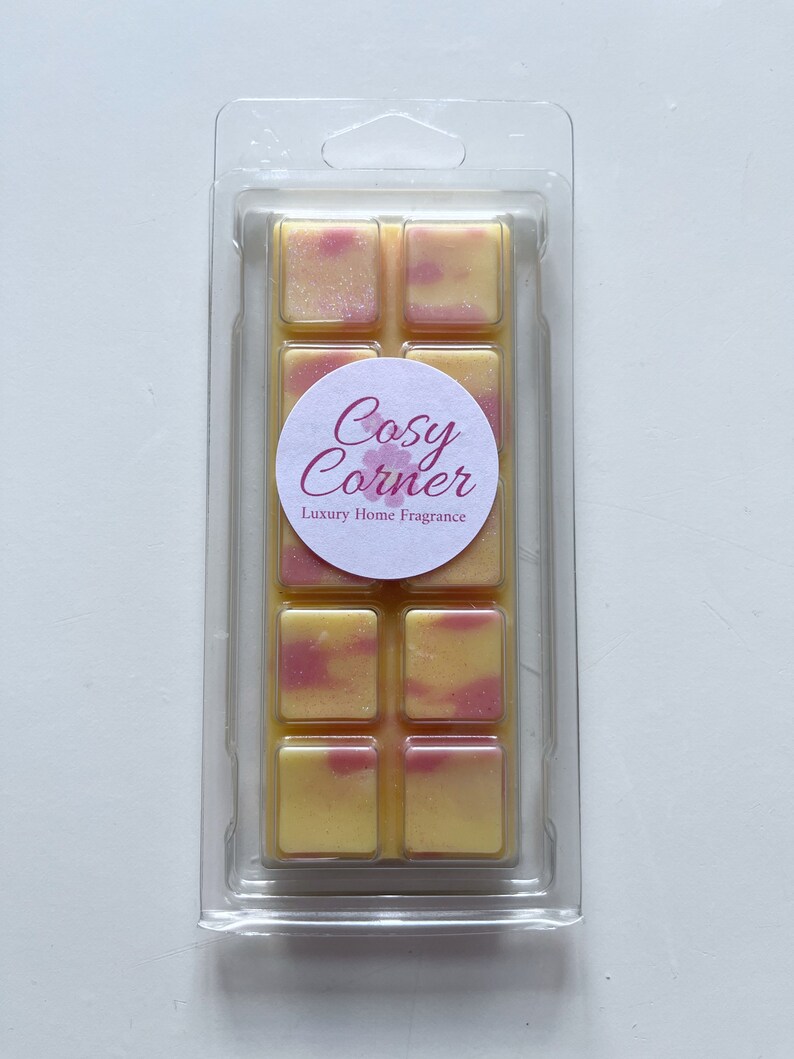 May include: A six-piece wax melt set in a clear plastic clamshell packaging. The wax melts are yellow and pink with a swirl pattern. The packaging has a white label with the text "Cosy Corner Luxury Home Fragrance".