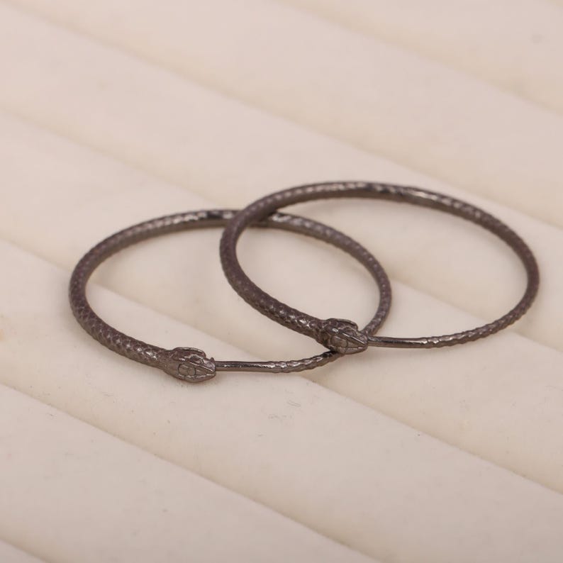 May include: A pair of black snake hoop earrings. The earrings are made of metal and have a textured finish.
