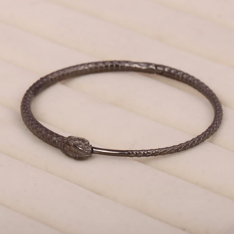 May include: A black snake-shaped bangle bracelet with a textured finish.