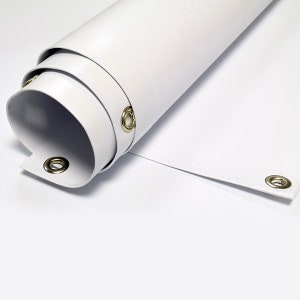 May include: Rolled white banner with brass grommets. The banner is made of a smooth, durable material and is partially unrolled, revealing the grommets along the edge. The banner is on a white background.
