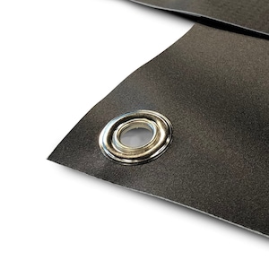 May include: Close-up of a section of black material with a silver grommet. The material has a textured surface and is folded over, revealing the grommet's shiny metal finish. The background is white.