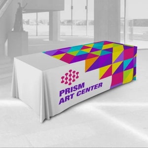 May include: White table cover with a colorful geometric design and the text "PRISM ART CENTER" printed on the front.