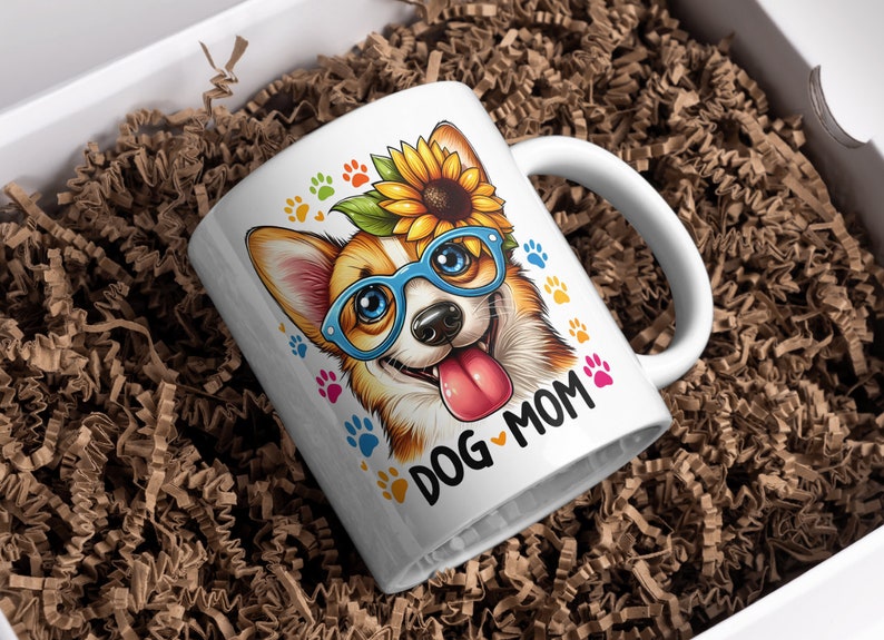 May include: White ceramic mug with a colorful illustration of a corgi wearing blue glasses and a sunflower on its head. The text "DOG MOM" is printed on the mug.