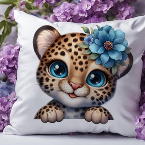 K&ouml;nnte beinhalten: Ein wei&szlig;es Kissen mit einem Cartoon-Bild eines Leopardenjungen mit blauen Augen und einer blauen Blumenkrone. Der Junge schaut &uuml;ber den Rand des Kissens.