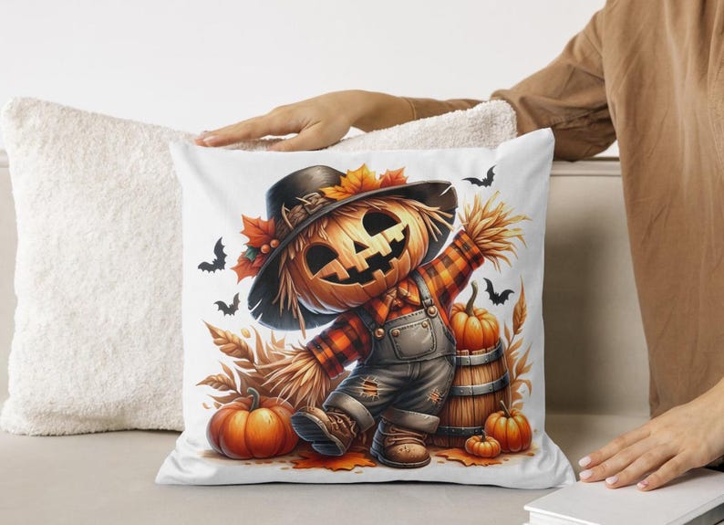 May include: A white pillow with a colorful illustration of a scarecrow with a pumpkin head. The scarecrow is wearing overalls and a plaid shirt. There are pumpkins and fall leaves around the scarecrow.