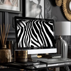 May include: A contemporary desk arrangement with a desktop computer displaying a zebra pattern. The desk includes a keyboard, a gold candle holder, and a black and white striped lamp. Decorative items and framed artwork complete the stylish workspace.