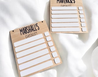 Può includere: Due liste di controllo in legno con spazi vuoti per scrivere. La lista di controllo superiore dice "Maverick's Checklist" e la lista di controllo inferiore dice "Marshall's Checklist".