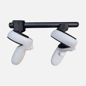 Könnte beinhalten: Zwei weiße VR-Controller mit schwarzen Akzenten sind an einer schwarzen Metallstange montiert. Die Controller sind nach unten geneigt und haben einen Knopf an der Vorderseite.