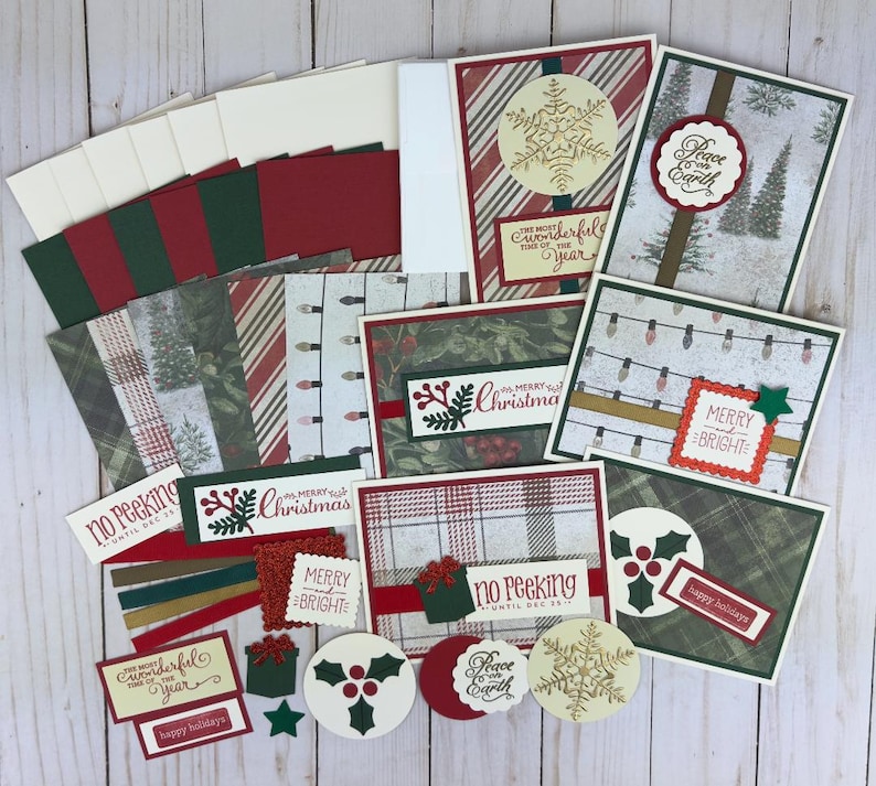 Puede incluir: Un conjunto de materiales para hacer tarjetas navide&ntilde;as que incluye cartulina estampada, sobres y adornos troquelados. Los dise&ntilde;os presentan copos de nieve, acebo, cuadros, luces de cadena y textos como Merry and Bright y Peace on Earth.