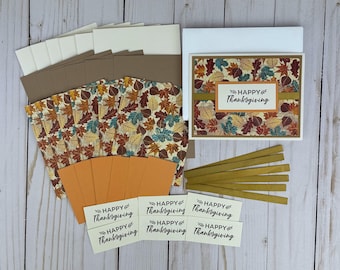 May include: Thanksgiving card-making kit with fall leaf patterned paper, blank cards, envelopes, and decorative accents. The kit includes cards with the text "Happy Thanksgiving". The color palette includes brown, orange, and cream.