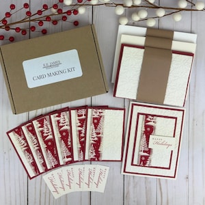 Puede incluir: Un kit para hacer tarjetas en una caja de cart&oacute;n marr&oacute;n etiquetada como E.E. James Stationery. El set incluye tarjetas color crema con patrones en relieve, papel con estampado de &aacute;rboles navide&ntilde;os en rojo y blanco y etiquetas Happy Holidays.