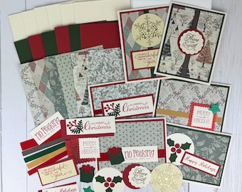 May include: A collection of Christmas-themed greeting cards and paper craft supplies featuring red, dark green, and cream cardstock. The set includes patterned papers with winter trees, holly, and snowflakes, along with labels reading Merry Christmas.