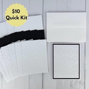 May include: A stationery set featuring white embossed cards with a damask pattern, black cardstock layers, and white envelopes. The set includes multiple folded cards and matching envelopes, with a yellow starburst graphic containing the text $10 Quick Kit.