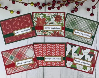Può includere: Sei biglietti d'auguri rettangolari con vari motivi natalizi, tra cui agrifoglio rosso, stelle di Natale, motivo scozzese verde, motivo scozzese rosso, rametti di foglie bianche e alberi di Natale stilizzati. Ogni biglietto ha un nastro e un'etichetta con la scritta merry christmas.