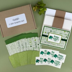 May include: A card-making kit with a brown box labeled "CARD MAKING KIT" and "E.E. JAMES STATIONERY." Includes green cardstock, patterned paper, and cards with shamrock designs and "Happy Patrick's Day" text. The kit is arranged on a green surface.
