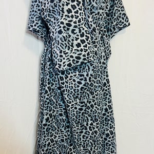May include: A flowing, floor-length dress featuring a black and white leopard print. The dress has short sleeves and a draped neckline. The fabric appears lightweight and suitable for warm weather. The overall style is casual and comfortable.