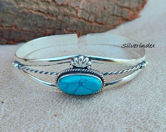 May include: A silver bangle bracelet with a turquoise stone set in a silver bezel. The bracelet has a twisted wire design and a decorative silver accent.