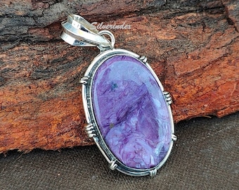 May include: A silver pendant with a purple and white stone set in an oval bezel. The pendant has a detailed silver bail.