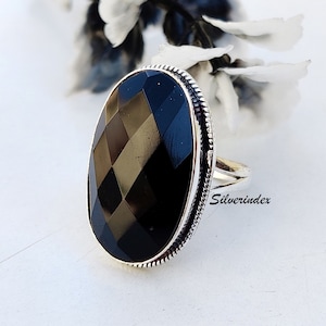 May include: A silver ring with a large, faceted black gemstone. The ring has a textured band and is set in an oval shape.