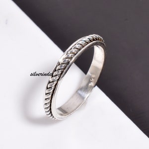May include: A silver ring with a braided design around the band.