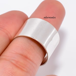 Peut inclure: Une bague large en argent, portée sur un doigt. La bague est lisse et polie.