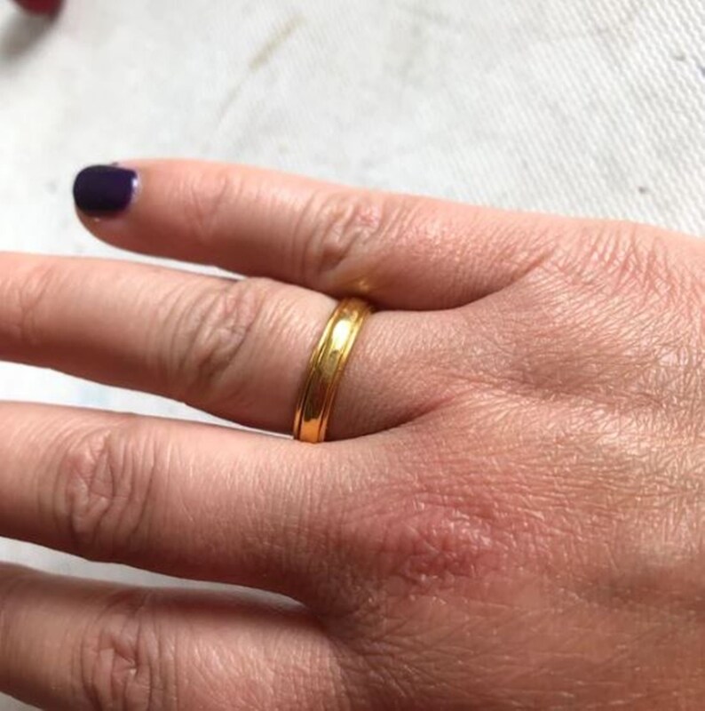 May include: A simple gold band ring with a slightly textured surface.