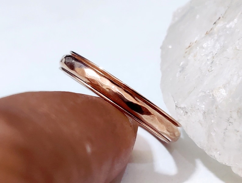 May include: A hammered rose gold band ring. The ring is simple and elegant, with a smooth, polished finish.