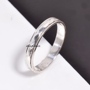 May include: A silver hammered band ring. The ring is simple and elegant, with a smooth, polished finish.